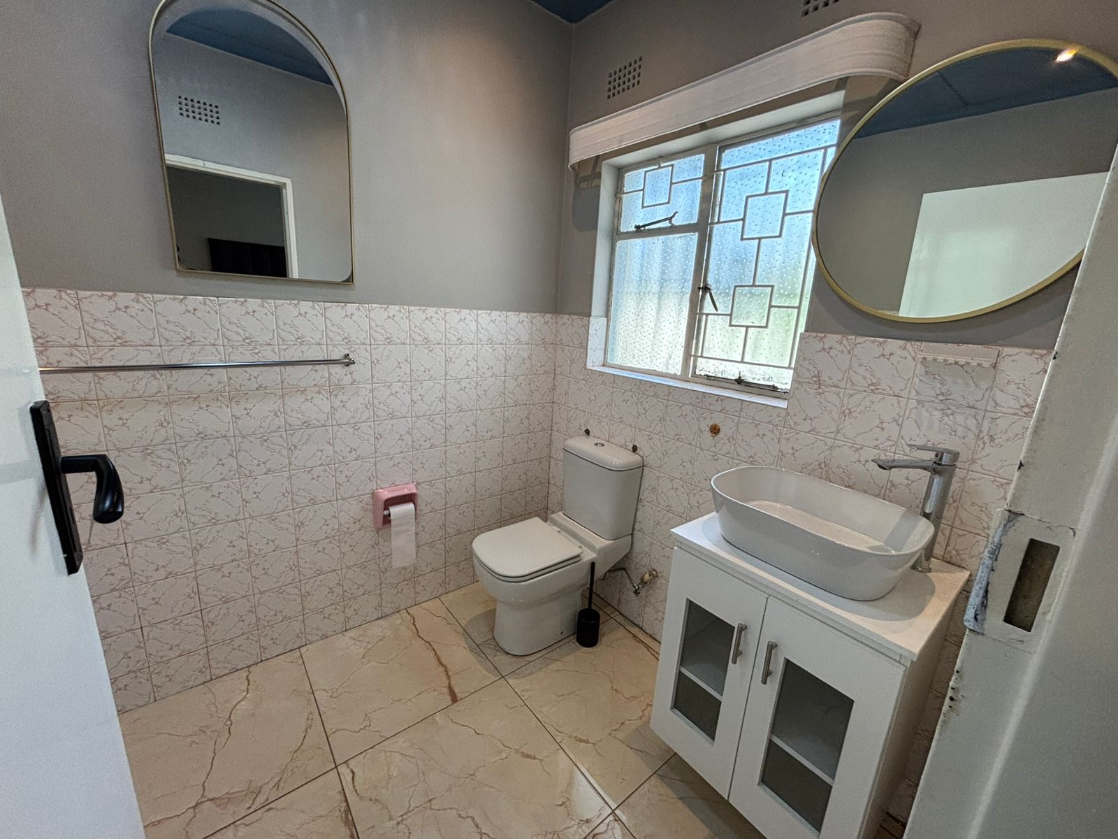 Bathroom with shower curtain, tub, vanity, and marble-look walls