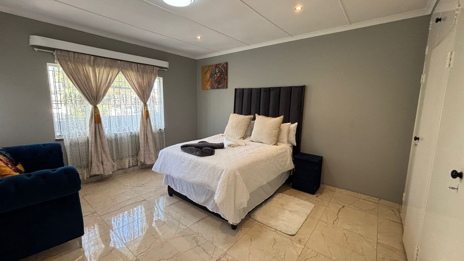 Bedroom with bed, blue sofa, and ensuite bathroom entrance