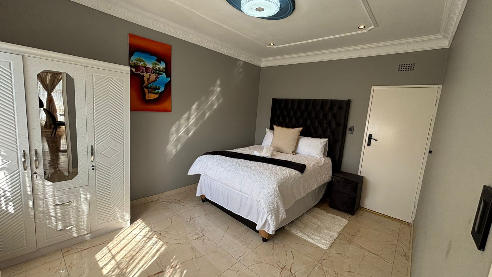 Bedroom with tufted headboard, towels, and side table