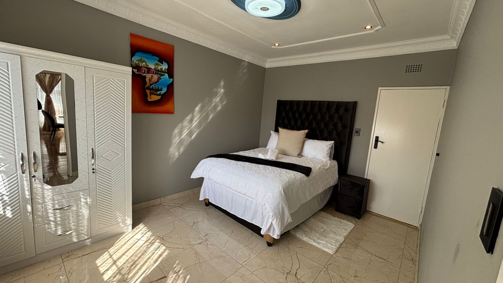 Bedroom with white wardrobe, bed, and framed wall art
