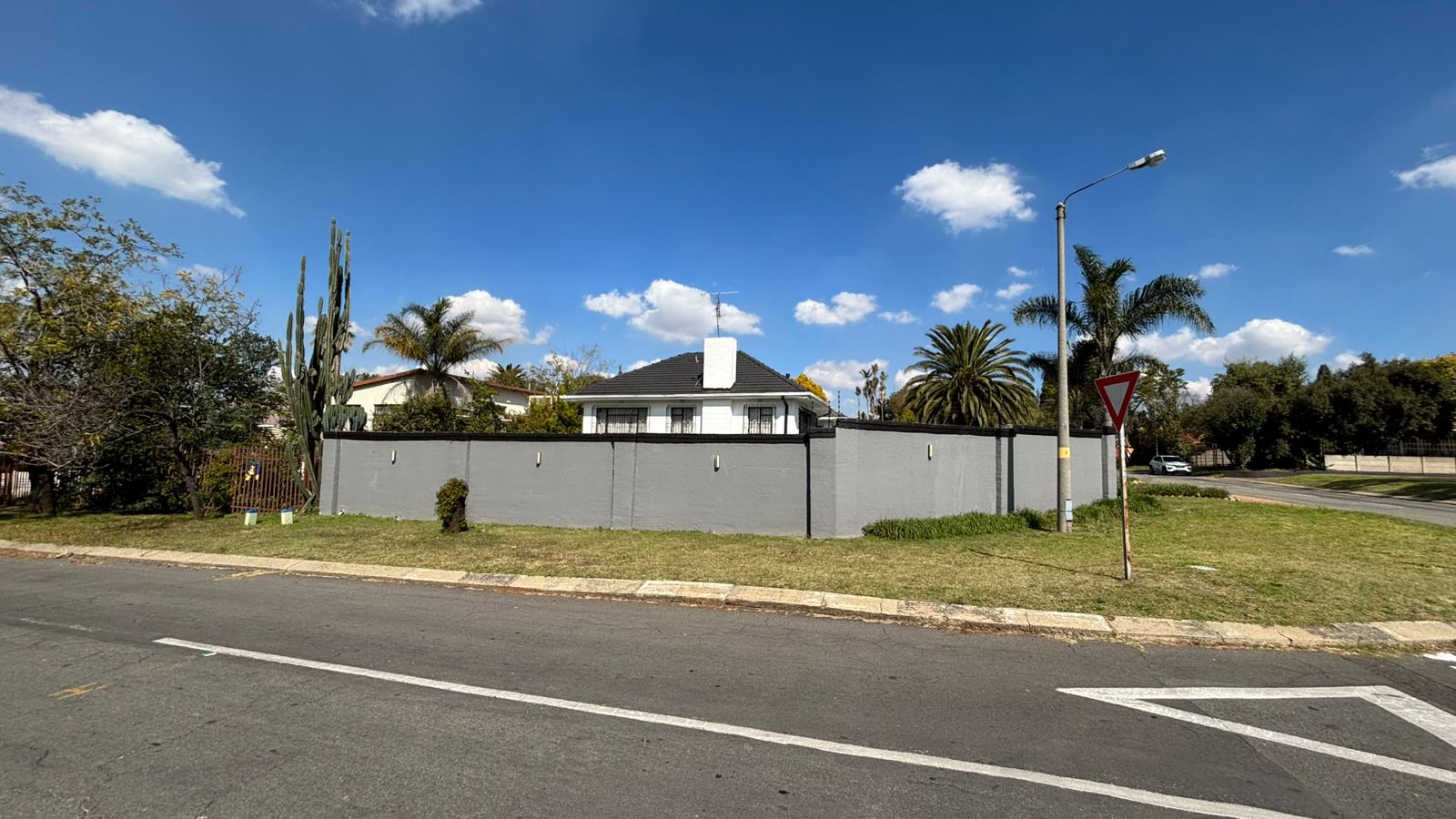 Corner street view of Bella Vista with white house and gray wall