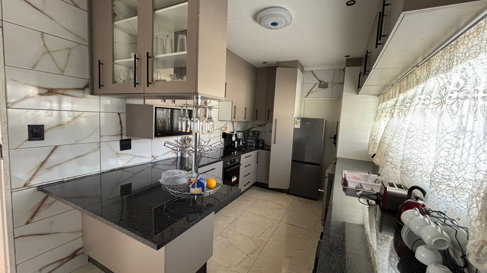 Modern self-catering kitchen with black counters and marble tile walls