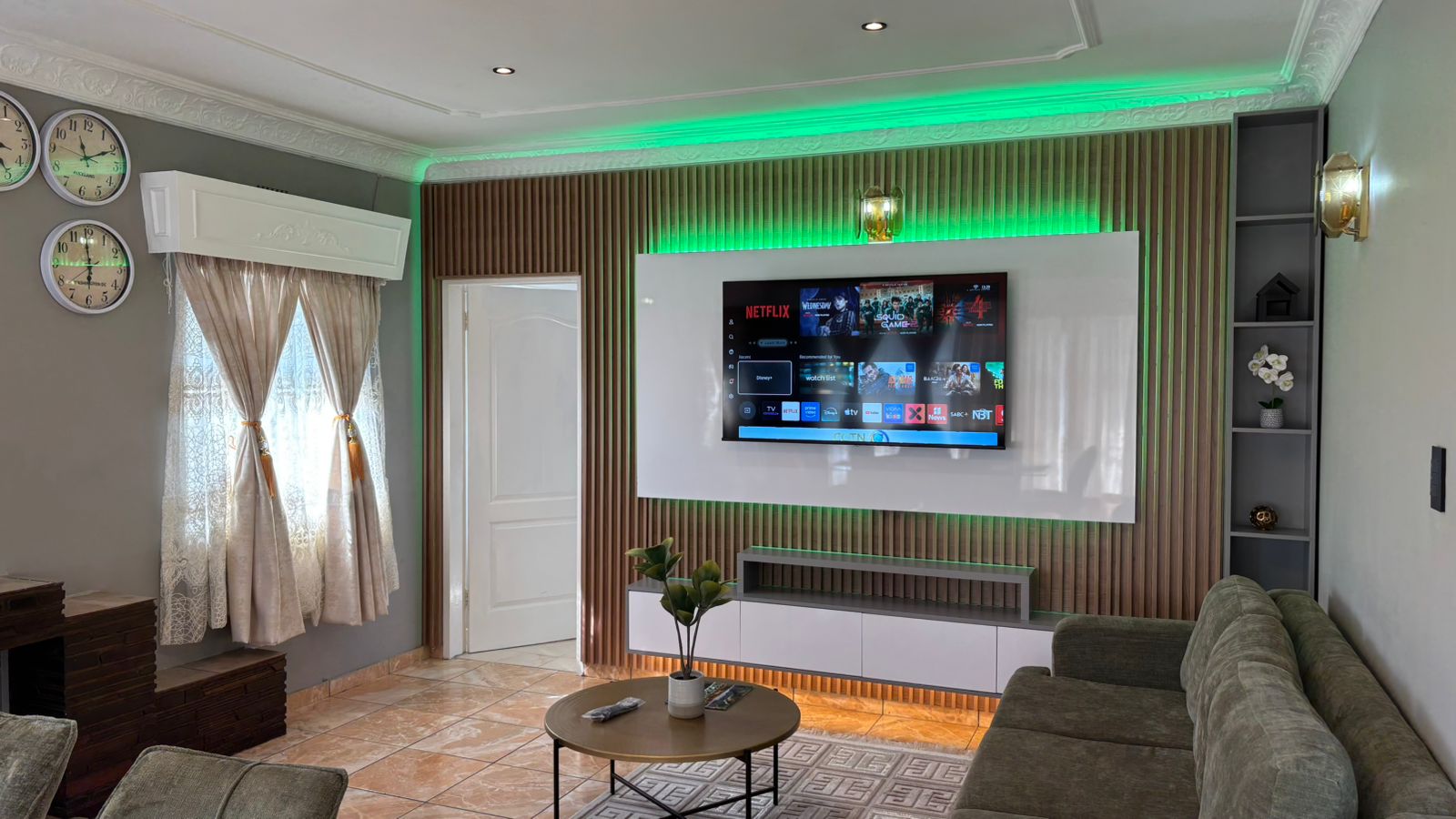 Living room with sofa, media wall, and green accent lighting